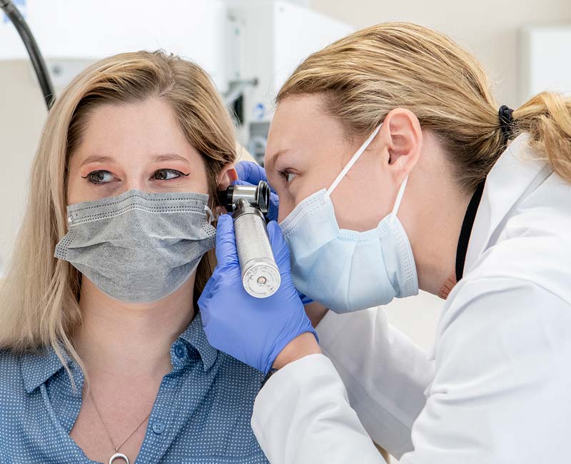 A nurse practitioner uses an otoscope to examine a patient’s ear during a physical exam.